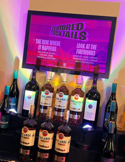 Electronic sign with featured cocktails; a tiered bar with rum and wine